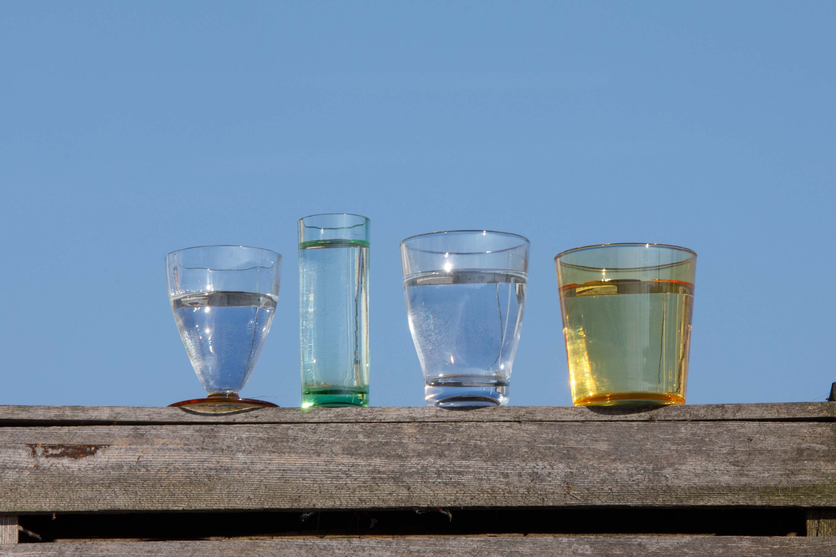 Four glasses of Drinking Water in front of blue sky.