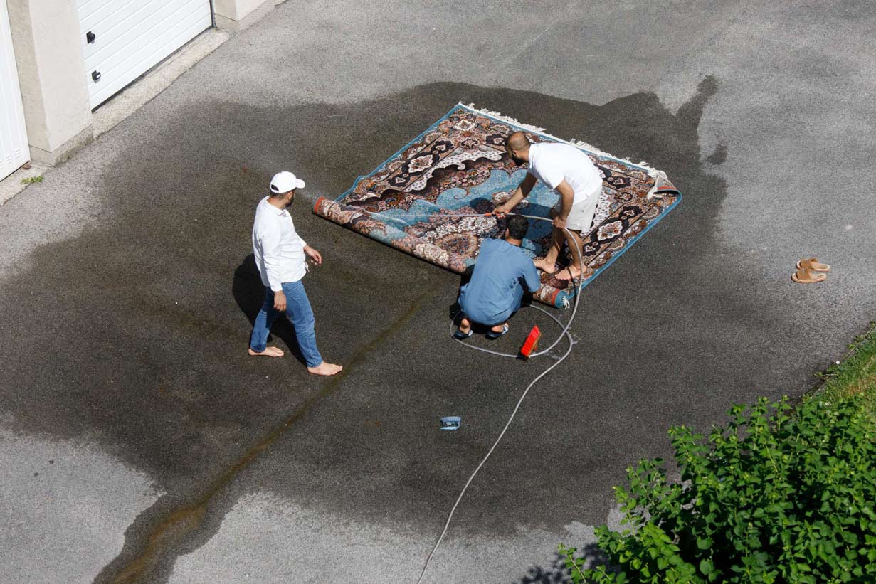 Men washing a carpet in a backyard 